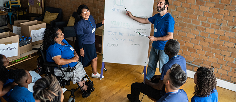 Mid adult man talking in a meeting at a community center - including a disabled person